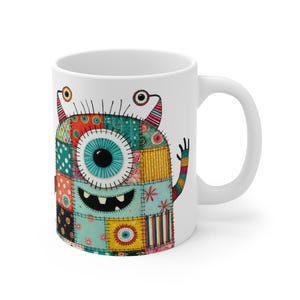 May include: White ceramic mug with a colorful patchwork monster design. The monster has one large blue eye, a toothy grin, and a patchwork body with various colors and patterns.