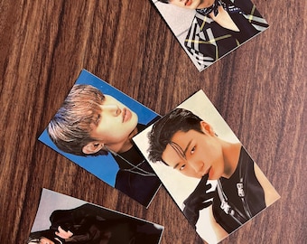 May include: Four photo cards featuring different men. Each card has a white border and a blue or gray background. The men are wearing different outfits, including a black leather jacket, a plaid shirt, and a black shirt with a silver chain.