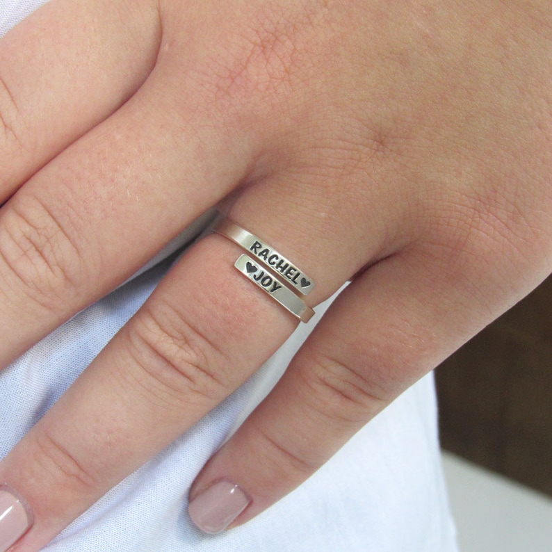 May include: A silver ring with the names "Rachel" and "Joy" engraved on it, separated by a heart symbol.