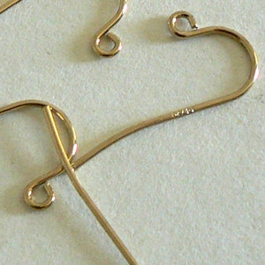 May include: Three gold-colored earring hooks, two are in the shape of a heart and one is a simple hook.