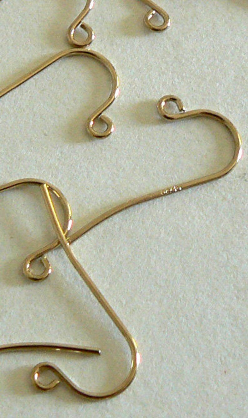 May include: Three gold-colored earring hooks, two are in the shape of a heart and one is a simple hook.