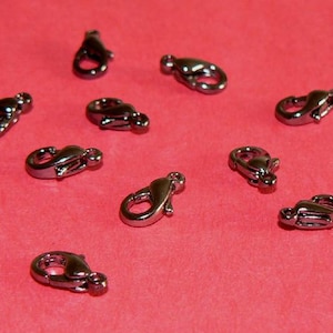 May include: Ten black metal lobster claw clasps, a type of fastener used in jewelry making.