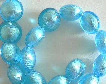 May include: A strand of light blue glass beads with a silver iridescent finish. The beads are oval shaped and have a slightly irregular surface.