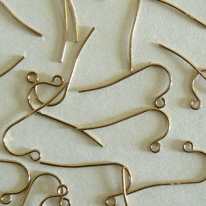 May include: A close-up of a group of gold-toned earring hooks. The hooks are made of metal and have a simple, elegant design.