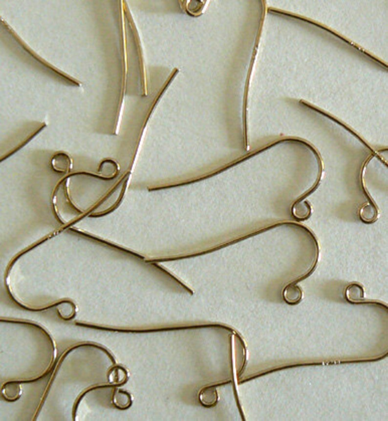 May include: A close-up of a group of gold-toned earring hooks. The hooks are made of metal and have a simple, elegant design.