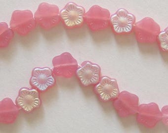 May include: A string of pink flower-shaped beads. The beads alternate between solid pink petals and translucent, iridescent centres. The beads are strung on a white string, ideal for jewellery making.