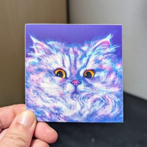 May include: A close-up of a white fluffy cat with yellow eyes and a pink nose. The cat is painted in a watercolor style on a purple background.
