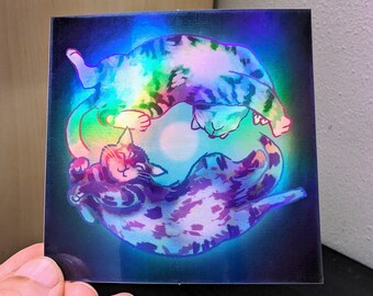May include: Two iridescent cats in a yin yang design, with a rainbow effect. The cats are curled up in a circle, with their tails intertwined. The background is a dark blue with a white glow in the center.