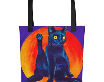 May include: A tote bag with black handles featuring a graphic of a black cat with bright yellow eyes sitting against a large, vibrant orange and red circular background. The cat is depicted in a painterly style with blue highlights.