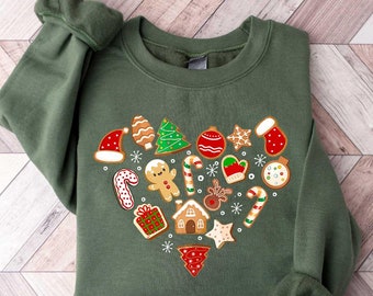 May include: A green sweatshirt with a heart-shaped design featuring gingerbread cookies, candy canes, and other Christmas-themed treats.