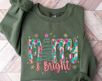 May include: A green sweatshirt with a Christmas tree design and the text "Merry & Bright" in gold glitter.