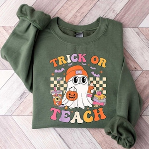 May include: Green sweatshirt with a ghost wearing a hat and holding a pumpkin. The text "Trick or Teach" is printed on the front.