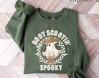 May include: A green sweatshirt with a white ghost wearing a cowboy hat and boots. The text "Boot Scootin' Spooky" is printed on the front of the sweatshirt.