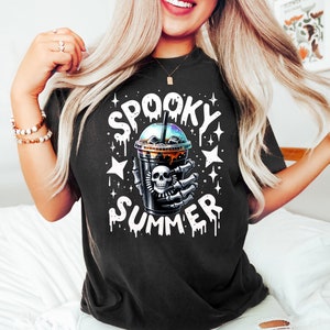 May include: Black t-shirt with a white graphic of a skull holding a cup of iced coffee with the text "Spooky Summer" dripping down the sides.