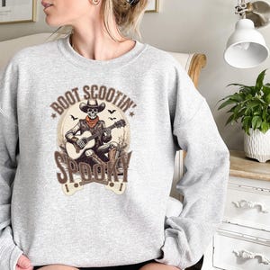 May include: Gray sweatshirt with a skeleton playing a guitar and the text "Boot Scootin' Spooky" printed on the front.