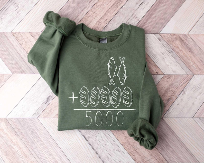 May include: A green sweatshirt with a white graphic of two fish and five loaves of bread. The text "5000" is below the graphic.