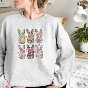 May include: A gray sweatshirt with a floral pattern bunny rabbit design. The bunnies are arranged in a grid pattern on the front of the sweatshirt.