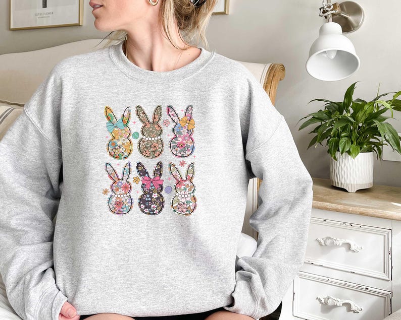 May include: A gray sweatshirt with a floral pattern bunny rabbit design. The bunnies are arranged in a grid pattern on the front of the sweatshirt.