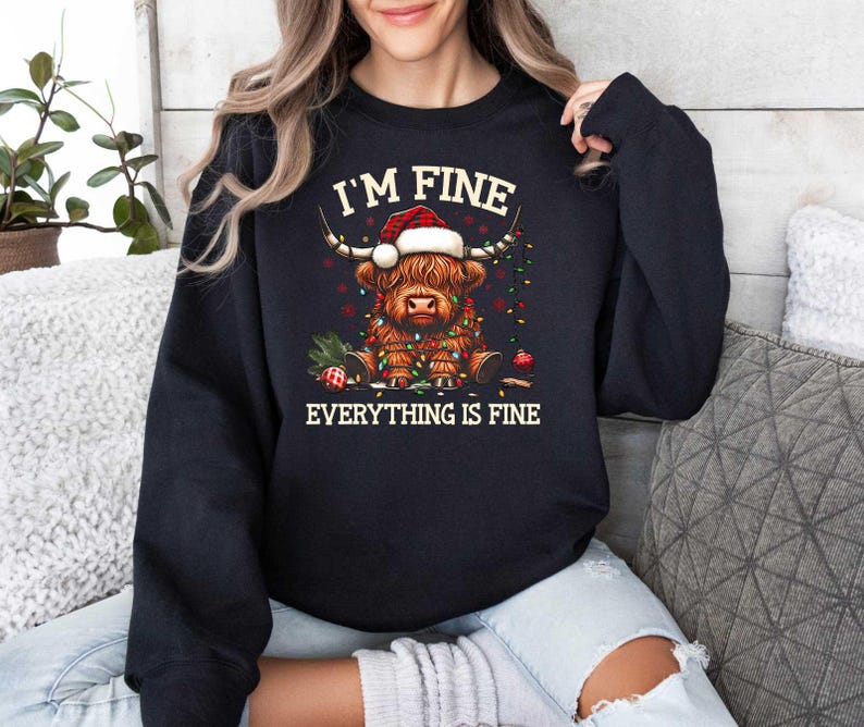 May include: Black sweatshirt with a graphic of a Highland cow wearing a Santa hat and surrounded by Christmas lights. The text "I'm Fine Everything is Fine" is printed below the image.