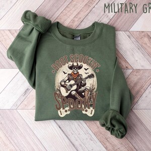 May include: A green sweatshirt with a skeleton playing a guitar and the text "Boot Scootin' Spooky" printed on the front.