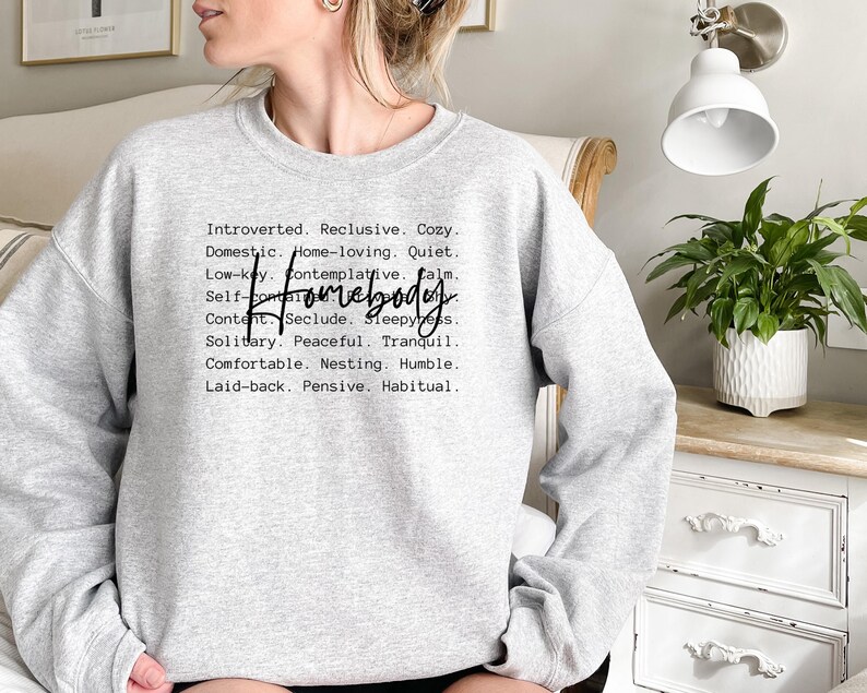 May include: Gray sweatshirt with the text "Introverted. Reclusive. Cozy. Domestic. Home-loving. Quiet. Low-key. Contemplative. Calm. Self-contained. Homebody. Content. Seclude. Sleepiness. Solitary. Peaceful. Tranquil. Comfortable. Nesting. Humble. Laid-back. Pensive. Habitual."
