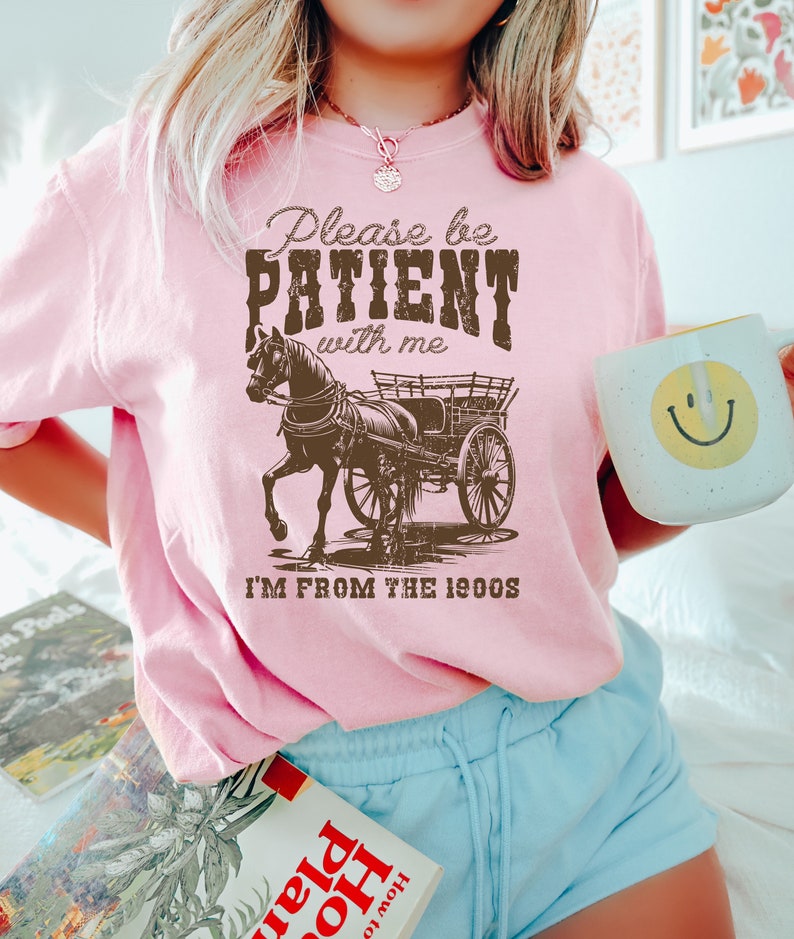 K&ouml;nnte beinhalten: Rosa T-Shirt mit einem braunen Pferdewagen-Motiv und dem Text "Please be PATIENT with me I'M FROM THE 1900s".