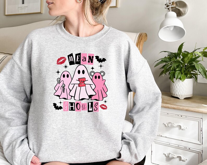 May include: A gray sweatshirt with a pink and black graphic design featuring ghosts and the text "Mean Ghouls".