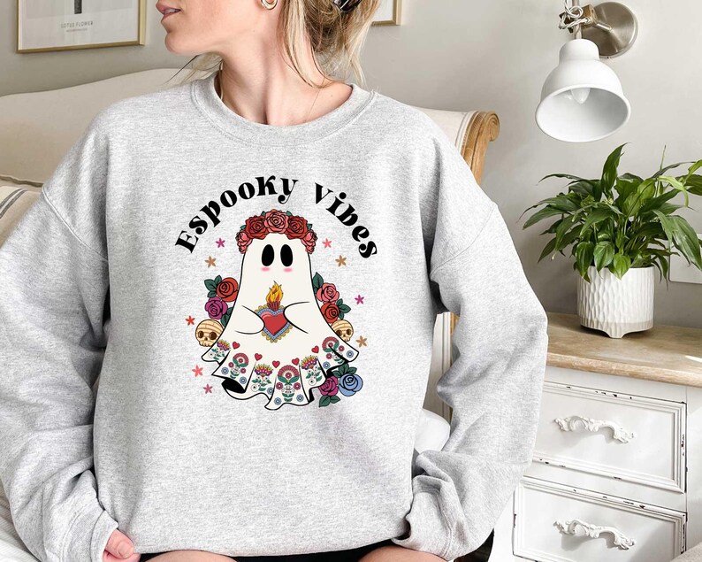 May include: A gray sweatshirt with a white ghost wearing a floral crown and holding a heart. The text "Spooky Vibes" is printed on the sweatshirt.