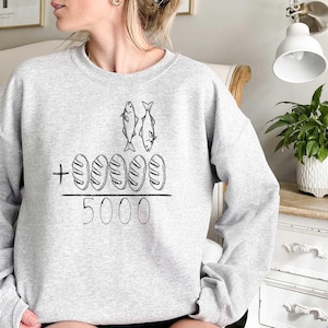 May include: Gray sweatshirt with a graphic of two fish and five loaves of bread with the text " + 5000" printed on the front.