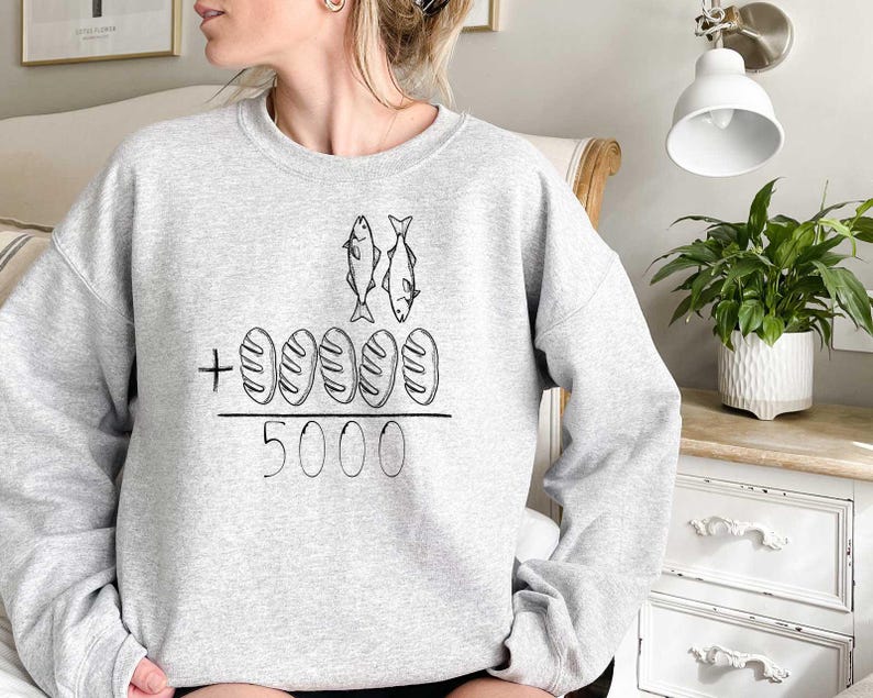 May include: Gray sweatshirt with a graphic of two fish and five loaves of bread with the text " + 5000" printed on the front.