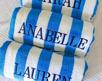 May include: Three rolled beach towels featuring vertical blue and white stripes. Each towel is embroidered with a name in dark blue thread: SARAH on the top towel, ANABELLE on the middle towel, and LAUREN on the bottom towel.