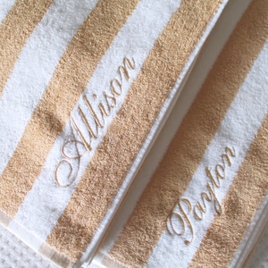 May include: Two white and beige striped towels with the names "Allison" and "Dayton" embroidered in white.