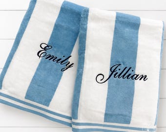 May include: Two plush towels featuring wide vertical stripes in white and light blue. Each towel is embroidered with a name in black cursive script, specifically the names Emily and Jillian, positioned centrally on the white stripe sections.