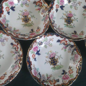 May include: Set of six vintage porcelain bowls with a floral pattern in shades of blue, red, and green. The bowls have a scalloped edge and a white background.