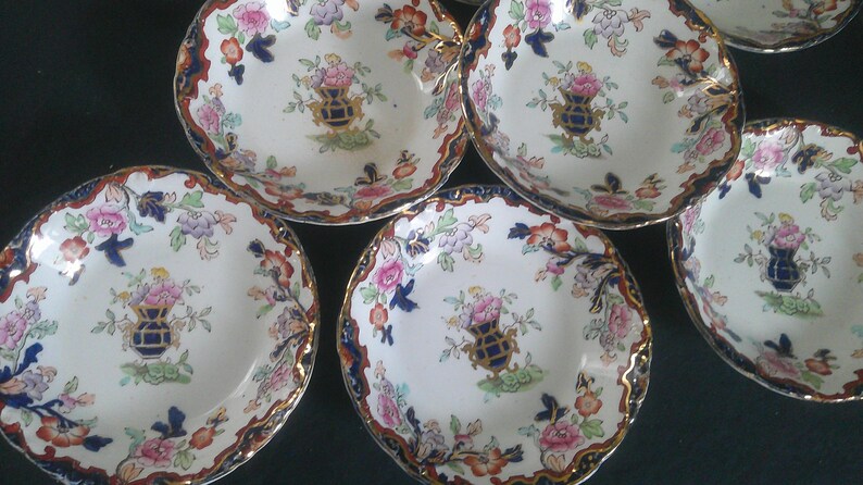 May include: Set of six vintage porcelain bowls with a floral pattern in shades of blue, red, and green. The bowls have a scalloped edge and a white background.
