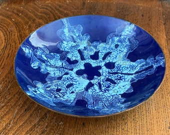 Könnte beinhalten: Eine kleine, blaue und weiße Keramikschale mit einem Schneeflockenmuster. Die Schale hat einen Kupferrand.