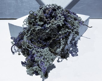 May include: A textured, hand-knitted scarf featuring a blend of deep purple, dark olive green, and light sage green yarn. The piece is constructed with a loose, curly, and open-stitch pattern that creates a voluminous, multi-dimensional appearance.