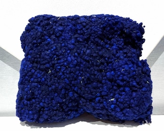 May include: A dark blue, textured headband. The headband is made of a thick, looped yarn, with a twisted design. The color is a deep, saturated blue with lighter blue highlights, creating a visually interesting surface.