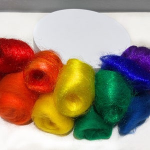 May include: A collection of colorful fiber bundles arranged in a rainbow spectrum. The colors include red, orange, yellow, green, blue, and purple. The fibers appear soft and slightly shiny, with a white background.