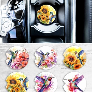 May include: Six sublimation car coasters featuring hummingbird designs. The coasters feature a variety of floral and watercolor backgrounds, including sunflowers, pink flowers, and blue and purple watercolor.