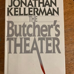 May include: A white book cover with the title "The Butcher's Theater" in gray text. The author's name, "Jonathan Kellerman", is printed in black above the title. The book cover features a red knife.