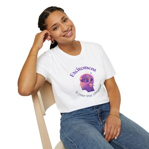 May include: White t-shirt with a purple graphic that reads "Excitement is your true vibration." The graphic features a silhouette of a head with a brain design. The shirt is made of a soft material.