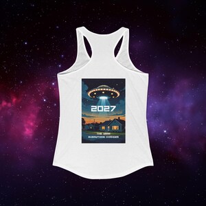 May include: White racerback tank top featuring a graphic of a UFO over a suburban neighborhood at dusk. The graphic includes the year "2027" and the text "The Year Everything Changes". The tank top is made of a soft, lightweight material.