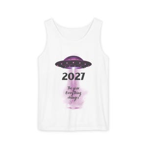 May include: White tank top featuring a purple UFO design with the year "2027" and the text "The year Everything changes." The UFO has a purple glow emanating from it. The tank top is a casual, sleeveless garment.