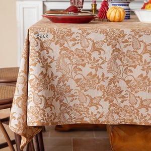 May include: A beige tablecloth with a brown floral pattern. The tablecloth is laid on a wooden table with a brown chair in the background. The text "Back" is visible on the tablecloth.