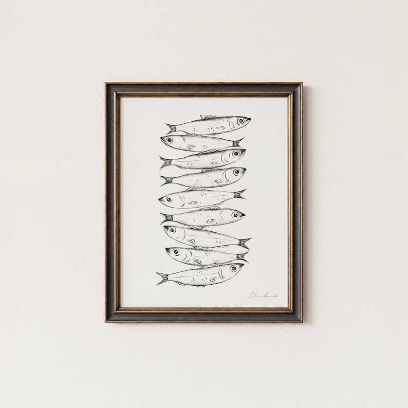 May include: A framed art print featuring a stack of stylized fish illustrations in black ink on a white background. The artwork is signed in the lower right corner and is set within a dark brown frame.