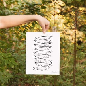 Nine whimsical sardines in a vertical line, each swimming in a different direction, line drawing print with moody, storybook, cottagecore style. Kitchen Decor Sardine print.