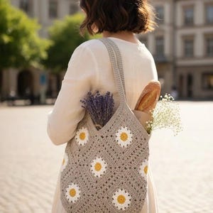 Puede incluir: Bolso tote de crochet gris con estampado de margaritas, llevado al hombro. El bolso contiene una baguette, lavanda y flores blancas. El bolso est&aacute; hecho de hilo suave y tiene un asa resistente.