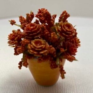 May include: A small terracotta pot filled with a cluster of faux orange and brown succulent plants.
