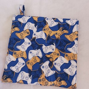 May include: A blue pot holder with a pattern of white and yellow video game controllers.